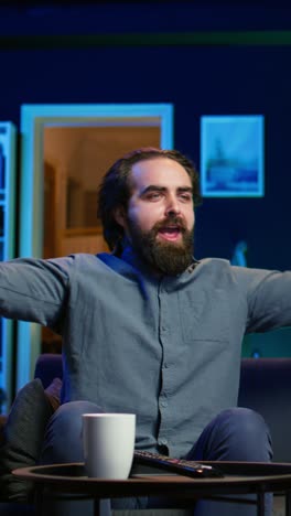 vertical video excited man at home enjoying football competition, clapping hands