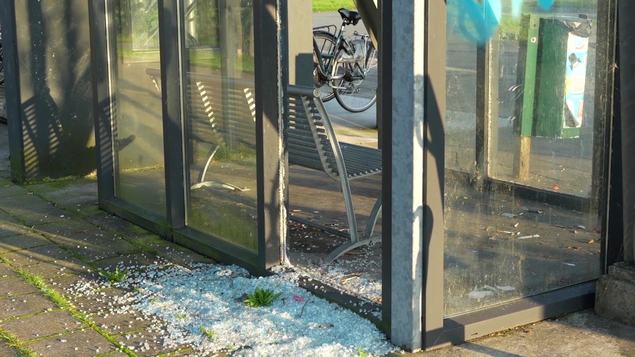 Glass fragments from smashed window at bus stop, signs of vandalism