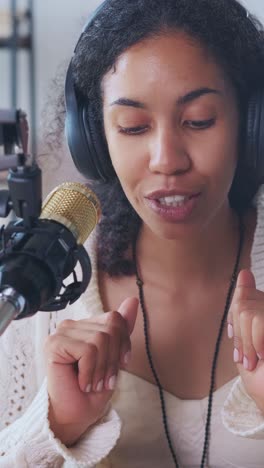 young african american woman radio presenter in recording studio with microphone