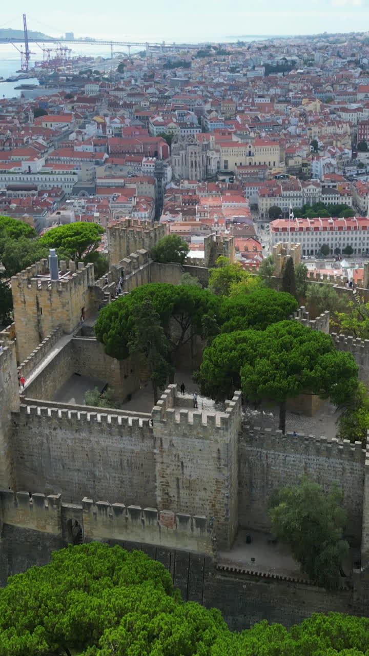 Aerial portrait shot orbiting the São Jorge Castle, sunny day in Lisbon, Portugal
