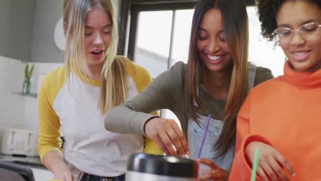 happy diverse teenager girls friends preparing healthy drink in kitchen, slow motion