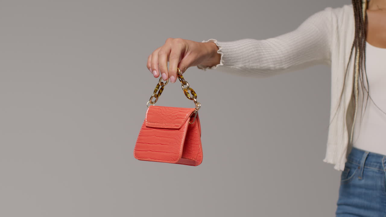 여성 소셜 미디어 인플루언서가 오렌지색 패션 드백을 들고 사용자 생성 콘텐츠를 제작하는 클로즈업