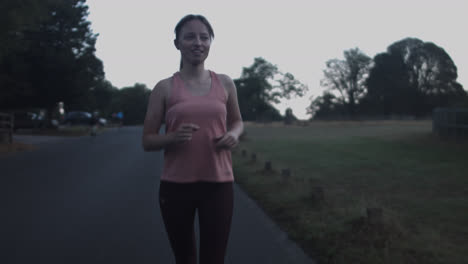 a young woman is running in the early morning in the park's road and passing by the cyclist