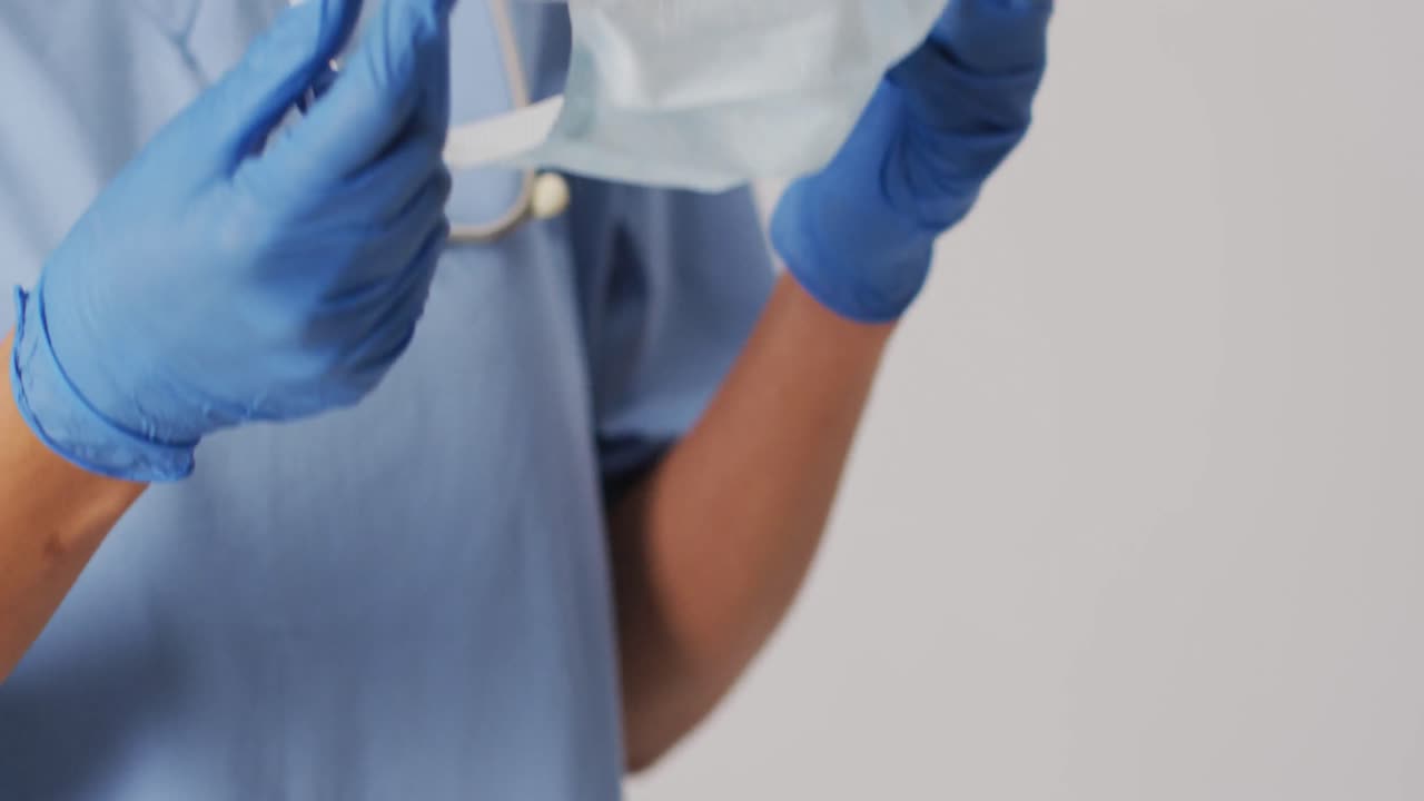 video de una doctora biracial con una máscara facial sobre un fondo azul