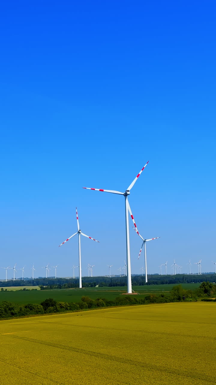 Wind turbines against bright blue sky. Renewable energy wind turbines spin in a green landscape under a clear blue sky on a sunny day