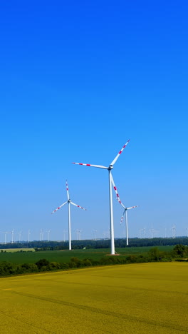 Wind turbines against bright blue sky. Renewable energy wind turbines spin in a green landscape under a clear blue sky on a sunny day