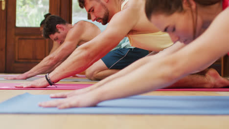 Heterogene-Gruppe-In-Yoga-Position-Dehnt-Sich-Auf-Matten-Während-Des-Yoga-Kurses-Im-Fitnessstudio