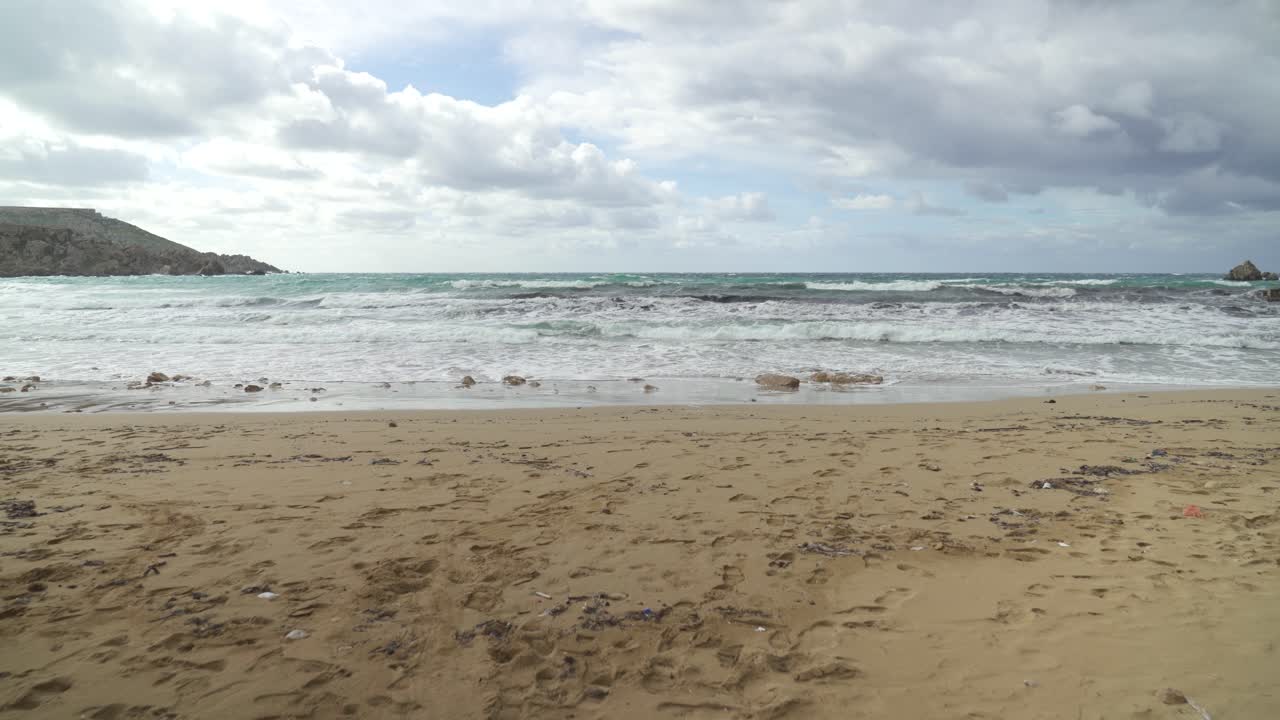 Spiaggia di Golden Bay in inverno con il Mar Mediterraneo mosso a causa del forte vento.
