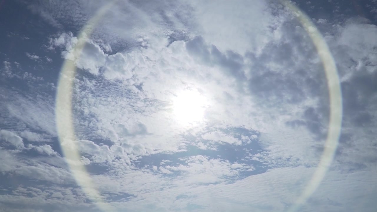 Solen gemmer sig bag skyerne på en blå himmel.