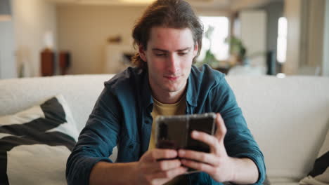 man using cellphone on couch indoors