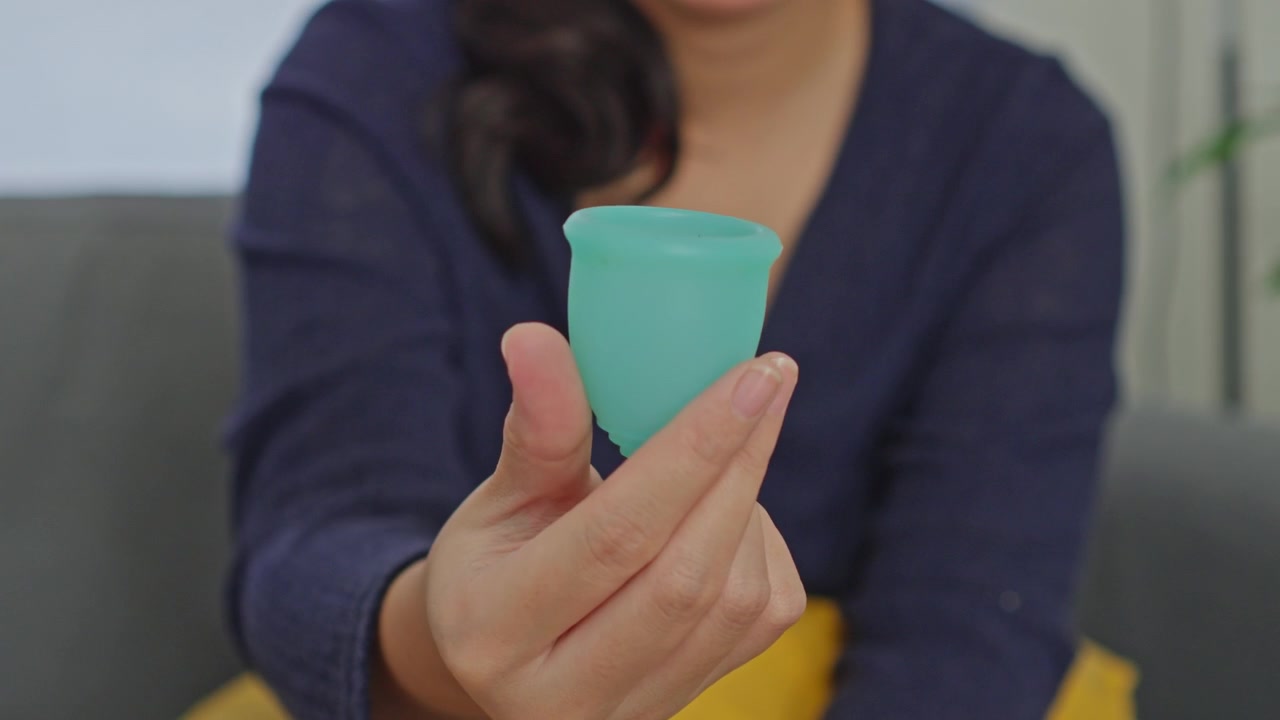 Woman's hand holding and showing menstrual cup for alternative period protection eco-friendly