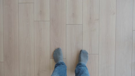 a person's feet standing on a wooden floor