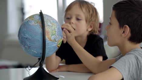 two caucasian boys spin a globe and dream about travel.