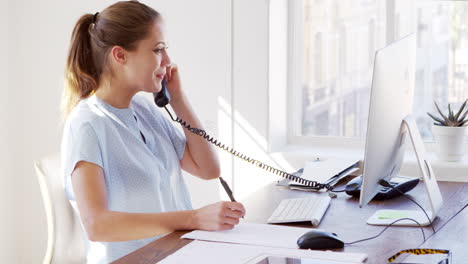 Una-Joven-Blanca-Terminando-Una-Llamada-Telefónica-En-Su-Escritorio-De-Oficina