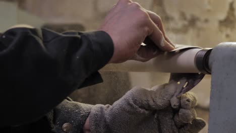 woodworker sanding a table leg with wood chips flying