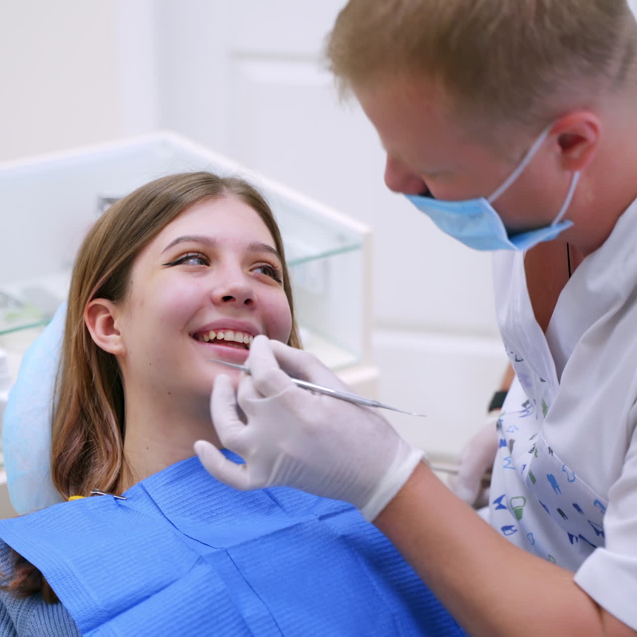 Beautiful woman with opened mouth at stomatologist. Professional dentist looks at patient's teeth using medical instrument in clinic.