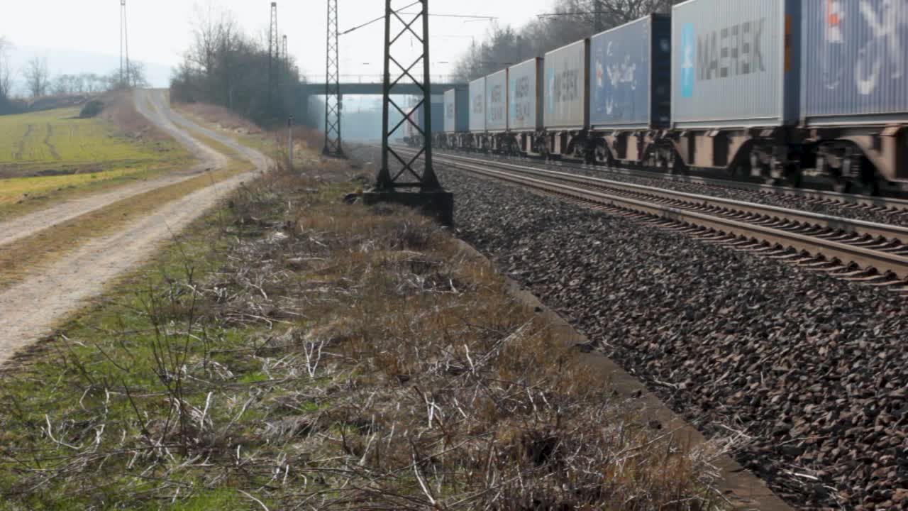 A freight train travels through a rural landscape on a sunny day, creating a serene scene