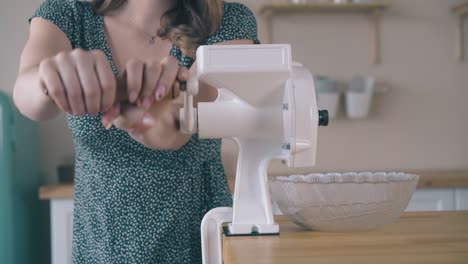 girl-makes-flour-turning-domestic-grinder-handle-in-kitchen