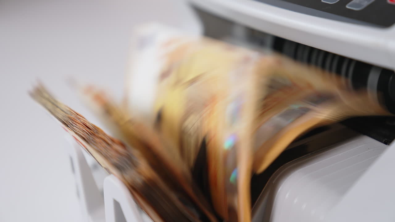 Counting fifty euro banknotes in cash counting machine. Orange bills turned very quickly in the equipment. Close up.