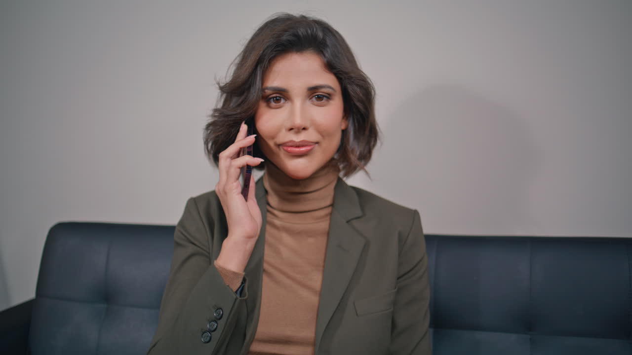 Joyful girl speaking mobile phone in contemporary office closeup. Cheerful woman