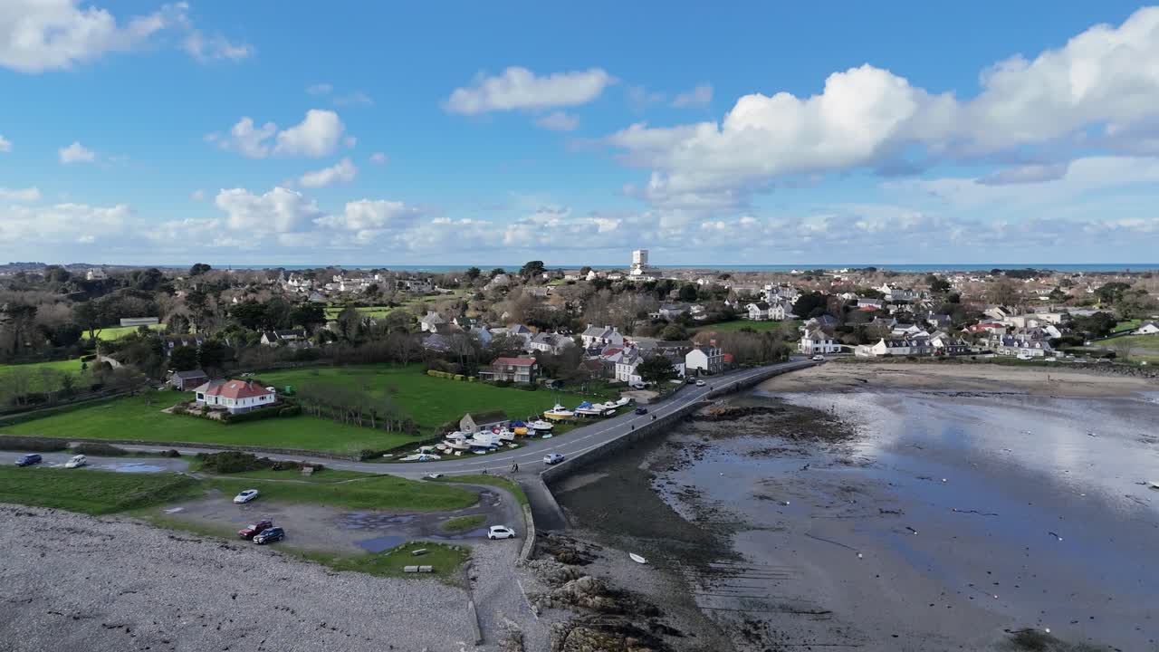 Bordeaux Harbour Guernsey high circling drone shot on sunny day with boats on hardstanding and views over beach to St Sampsons