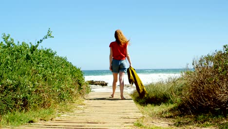 woman walking towards sea on boardwalk 4k