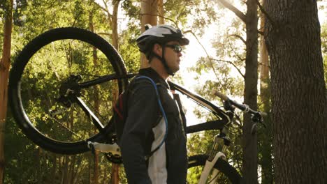 male mountain biker carrying bicycle in the forest