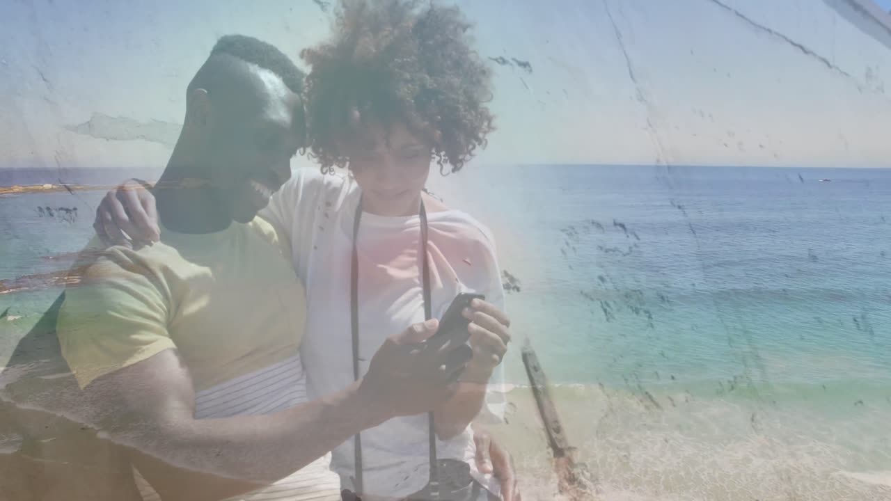 animación de una feliz pareja afroamericana usando un teléfono inteligente en la playa sobre el mar
