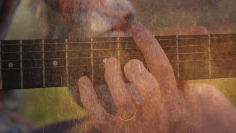 male musician's left hand pressing guitar strings for music demo, featuring animated dust overlay