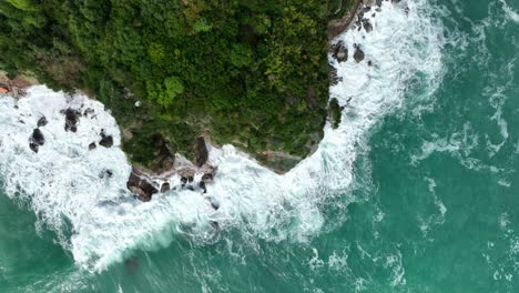 aerial: rocky cliff and adriatic sea with waves crashing during the day in montenegro, top down drone shot