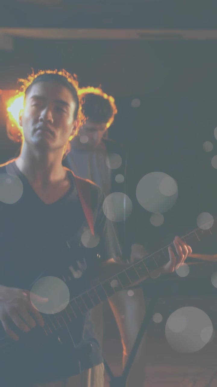 Video verticale: Telecamera in avvicinamento, bassista che suona il basso con la band in prova, mentre il bokeh sfuma in primo piano.