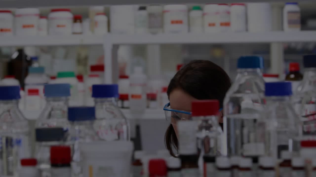 Man leaning in and starting HUD while woman examining lab vials, analyzing samples for research
