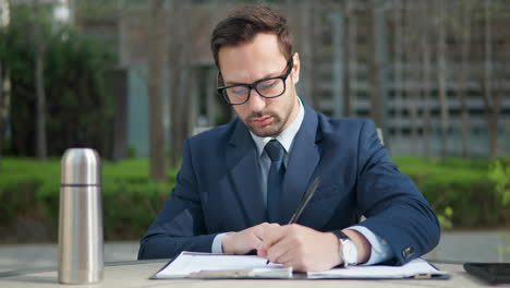 joven hombre de negocios barbudo pensando y escribiendo notas o resaltando en un parque verde