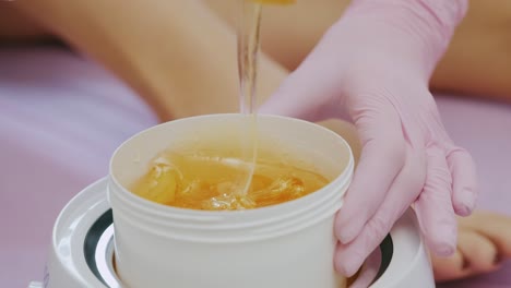 liquid sugar for skin epilation. close up shot. depilation and beauty concept - sugar paste or wax honey for hair removing with wooden waxing spatula sticks