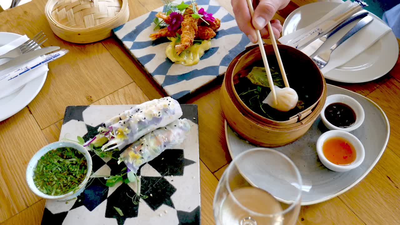 European hand uses chopsticks to eat dim sum, tempura prawn and rice paper rolls