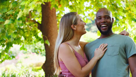 retrato de una pareja amorosa de varias razas de pie al aire libre en un parque de jardín o en el campo