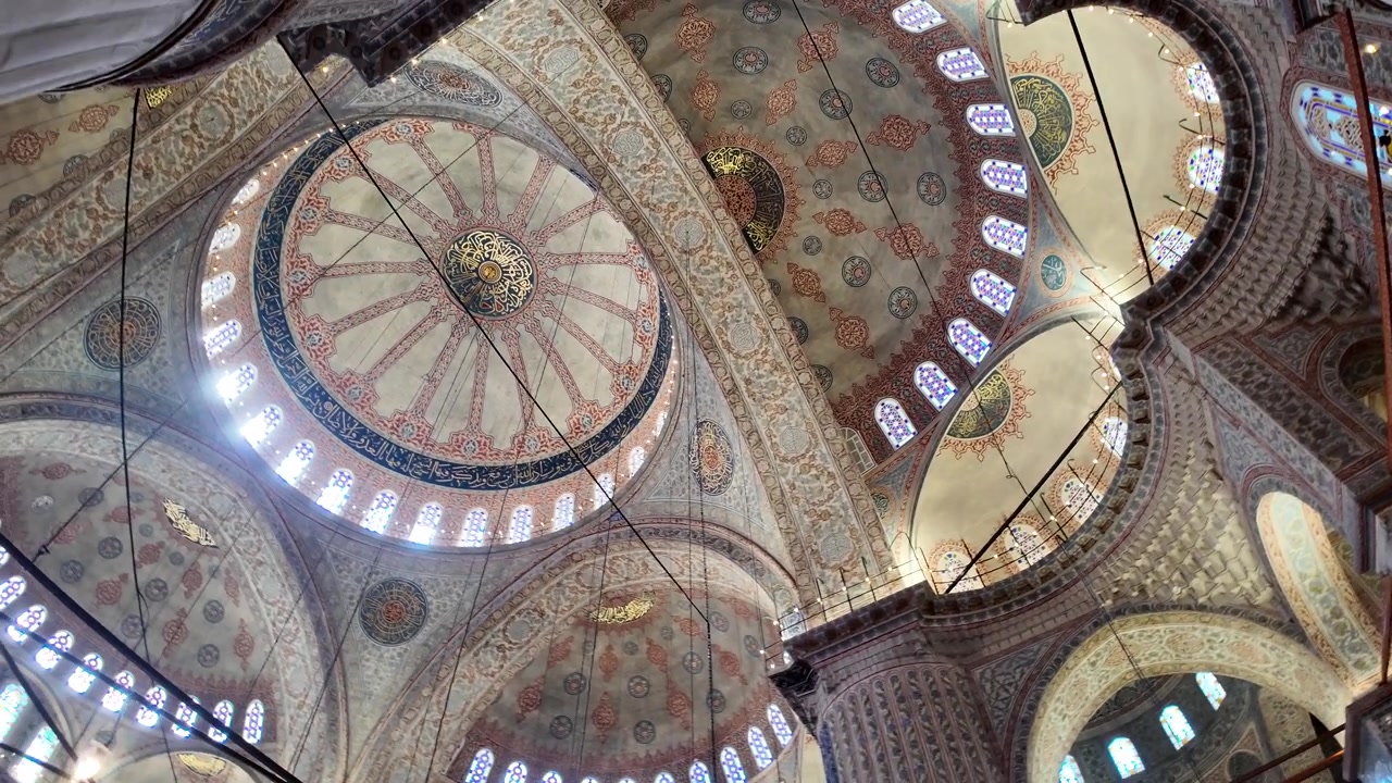 Grandi cupole e calligrafia ornata all'interno di una moschea storica.
