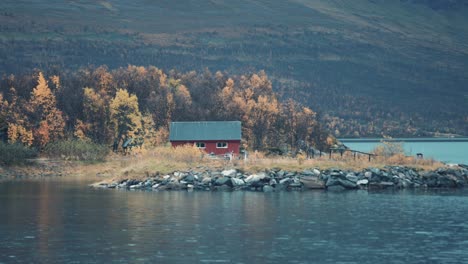 a small red fishing hut on the shore of the fjord