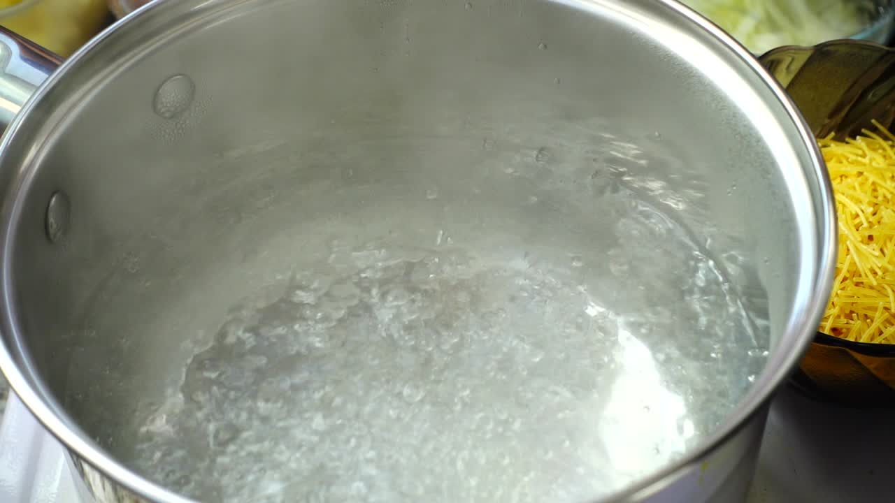Add salt to boiling water in a metal pan close-up