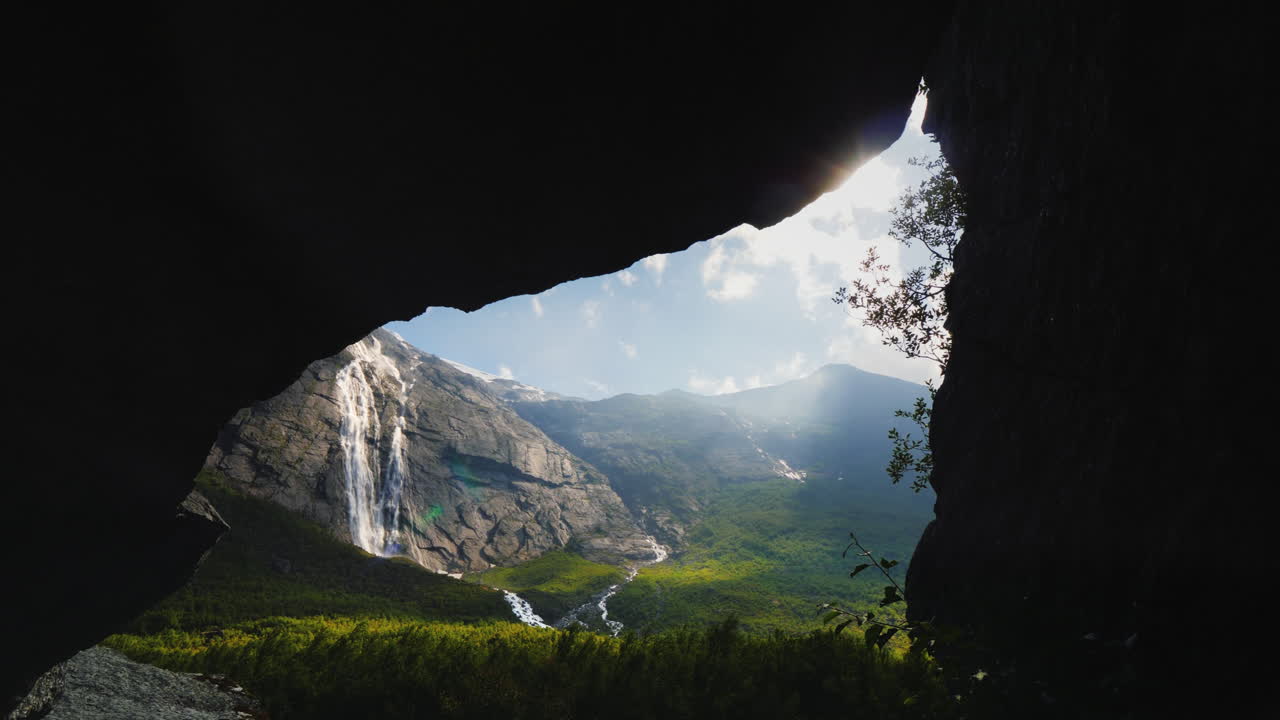 un hermoso valle rodeado de rocas y una cascada en la vista superior a través del arco en la roca