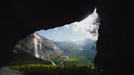 a beautiful valley surrounded by rocks and a waterfall at the top view through the arch in the rock