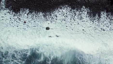 ocean waves crashing on a volcanic black sand beach