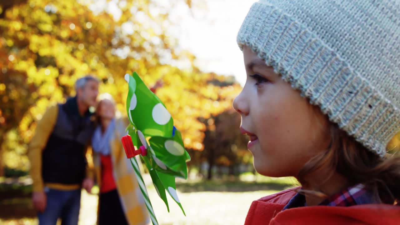 소녀는 배경에서 부모와 함께 장난감을  ⁇ 고 있습니다.