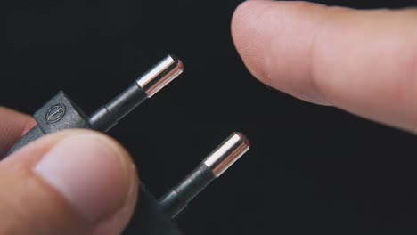 man shows european plug in black plastic case at darkness