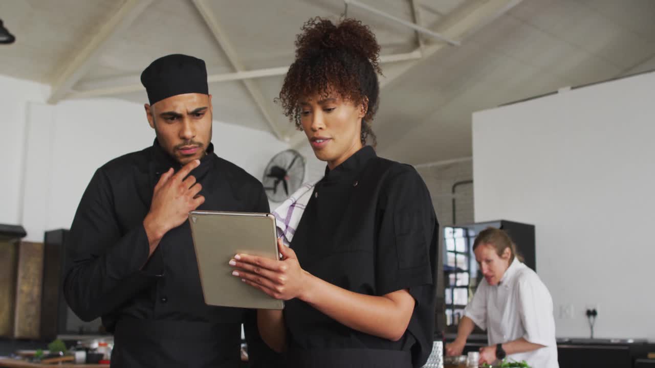 cocineros de raza mixta masculinos y femeninos que usan tableta digital