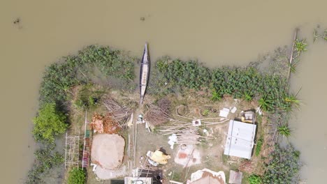 aerial top view of an isolated house surrounded by flood water. boat moored in front of the home. bangladesh, south asia, sylhet