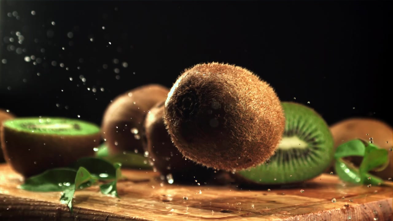 Kiwi fresco che cade e schizza acqua su una superficie di legno