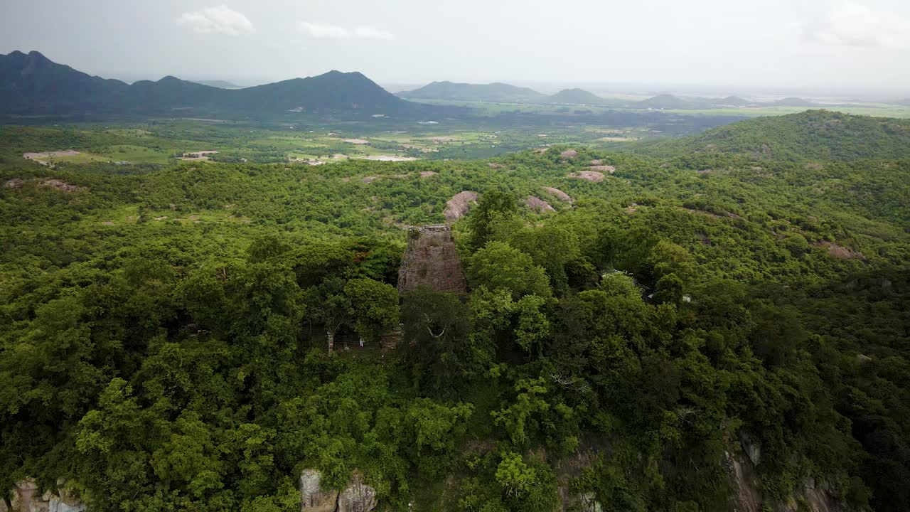 Angkor temple on mountain top in the lush low lying hills of Cambodia bordering the Vietnam border.  Drone aerial rotate orbit of Phnom Bayong.