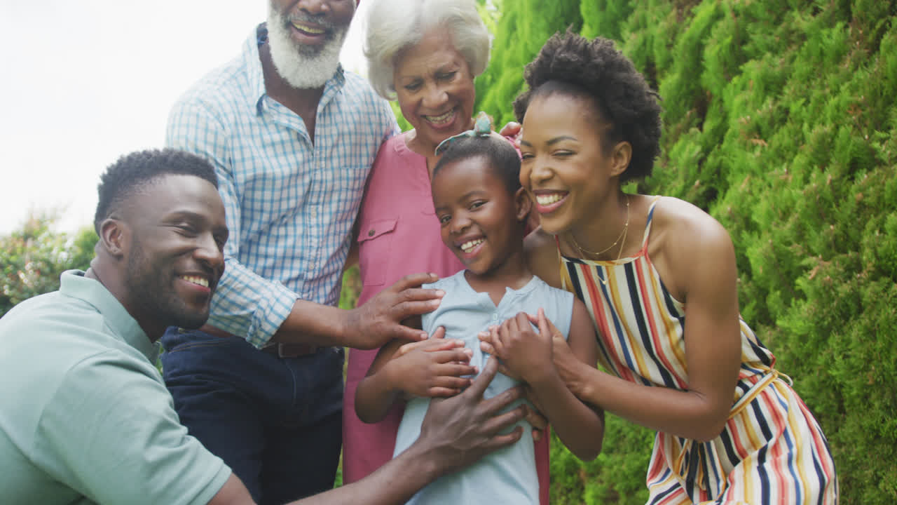 Portrait of happy african american family embracing and smiling in garden