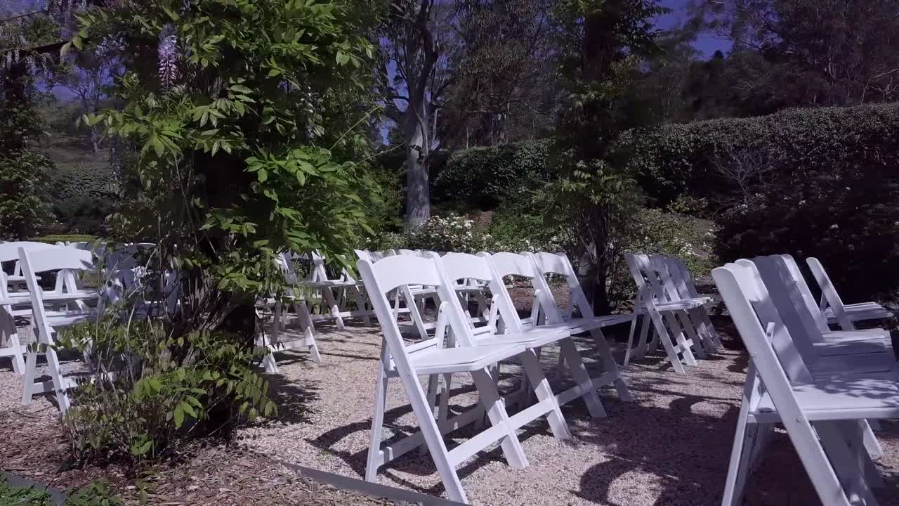Sedie bianche disposte in file in una location per matrimoni in giardino